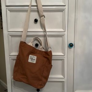 Tan crossbody bag with two exterior side pockets and one pocket inside.